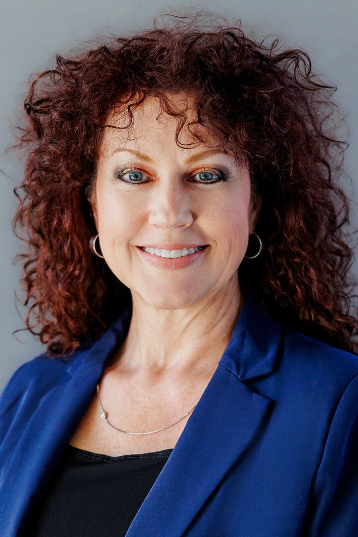 Melanie Modica Smiling woman with curly auburn hair.