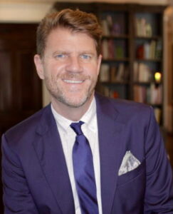 Smiling man in a purple suit.