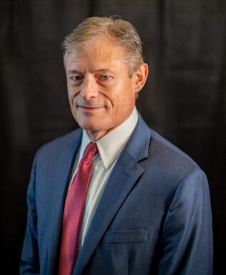 Confident gray-haired man in navy blazer.
